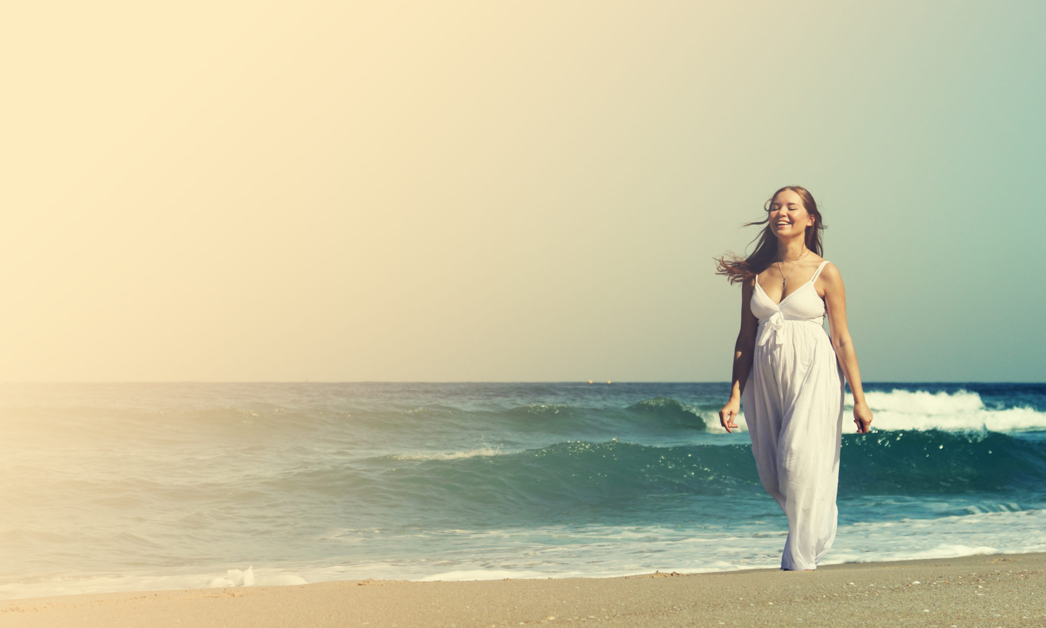 woman smiling and walking on beach