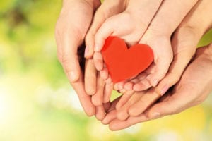 family hands surrounding heart