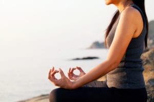 woman meditating on the beach