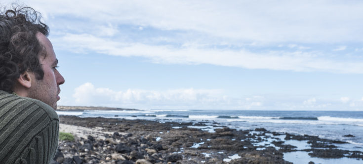 man looking at rocky beach