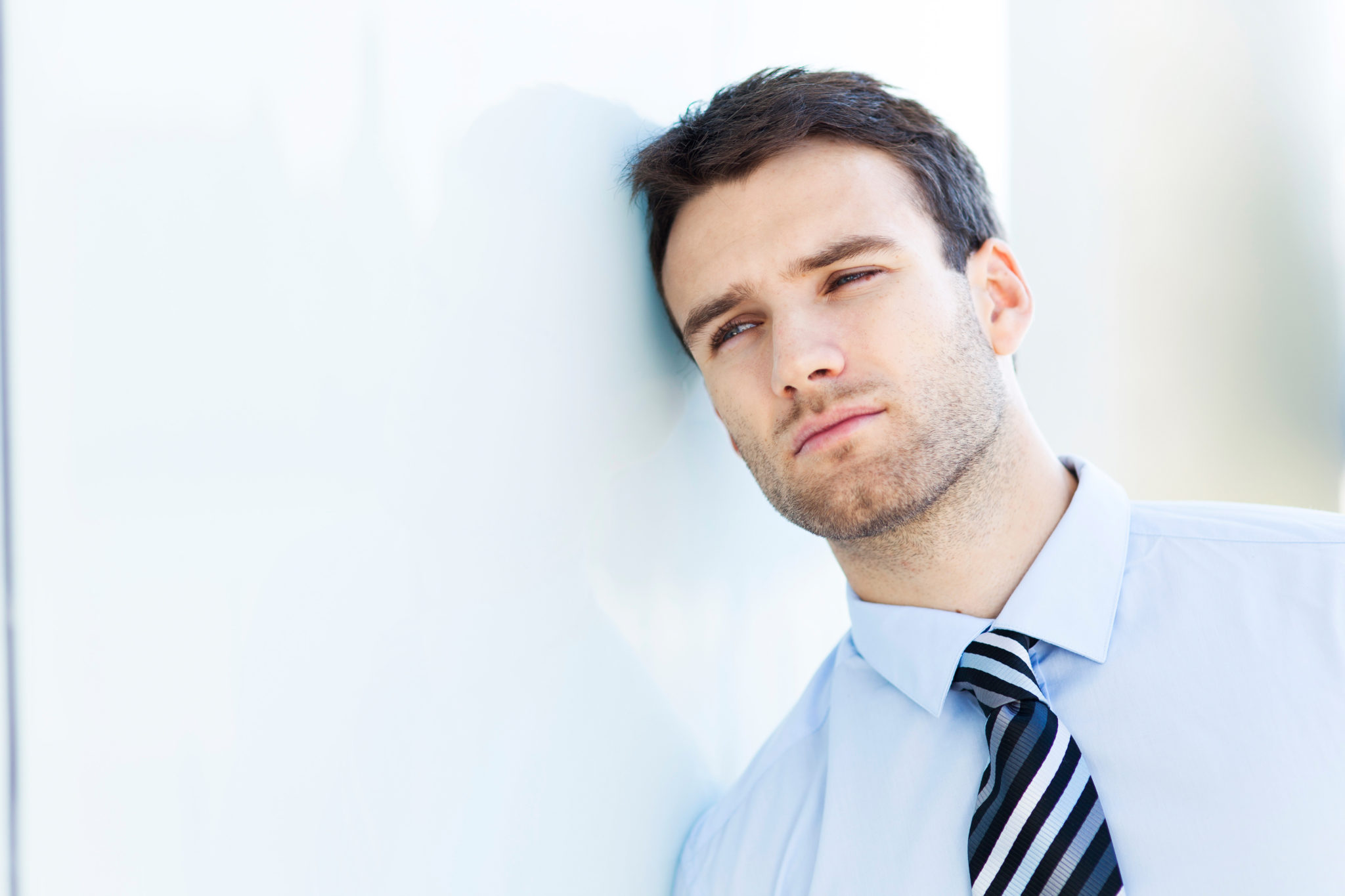 man leaning on white wall