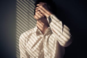 man holding face in spotted sunlight