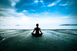 woman on beach in mindfulness pose