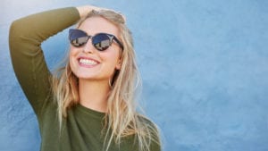 woman with sunglasses smiling at sun