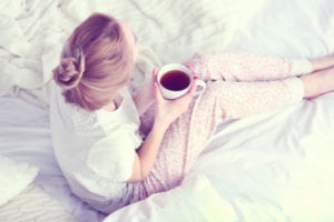 woman in bed drinking tea