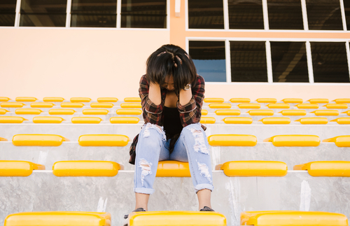 woman on bleachers with head in hands