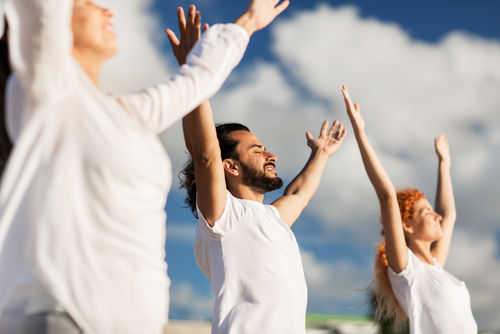 people with arms outstretched to blue sky