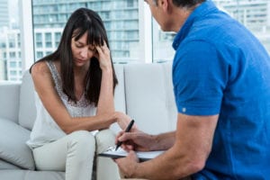 Woman looking down while talking to male therapist