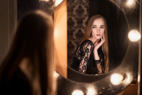 woman looking at self in mirror with lights