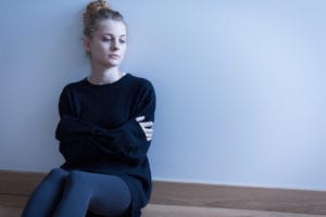 sad woman sitting by a wall