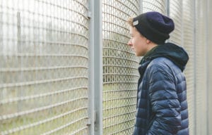 kid looking through chain fence