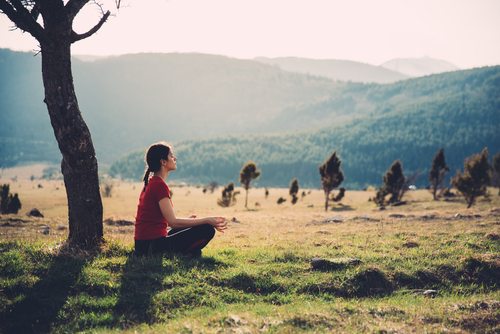 woman meditating out by tree