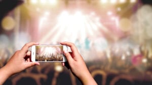 person taking photo on phone at concert