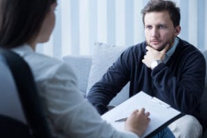 man with hand on chin looking at counselor