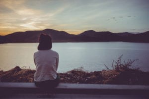 woman facing away from camera staring at water