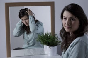 woman looking at camera with other image of her in mirror