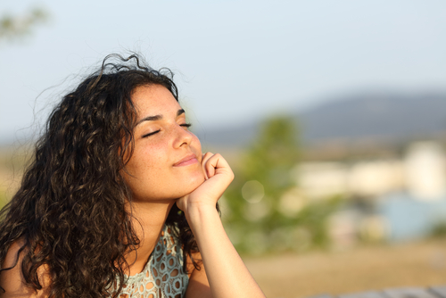 young woman with eyes closed smiling into sun