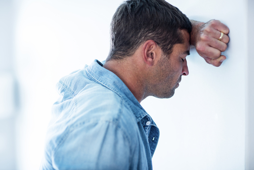 man leaning on hand at wall