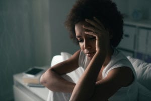 woman holding forehead in bed