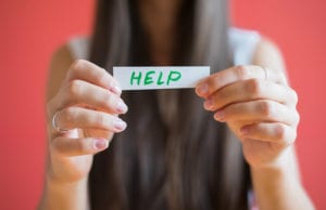 woman holding HELP written on paper