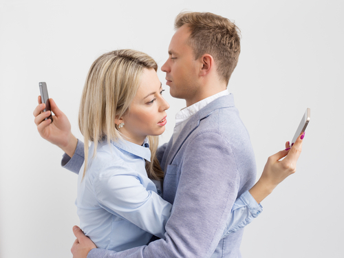 couple hugging and looking at phones