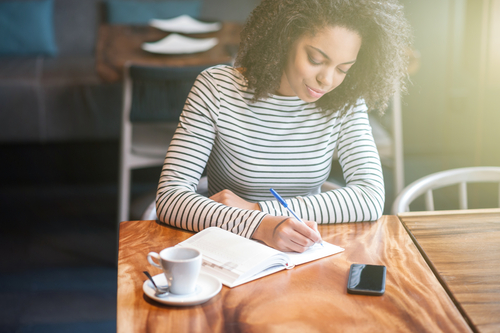 woman writing in coffeeshop