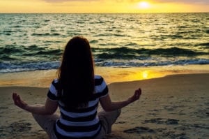 woman in clothes meditating on beach