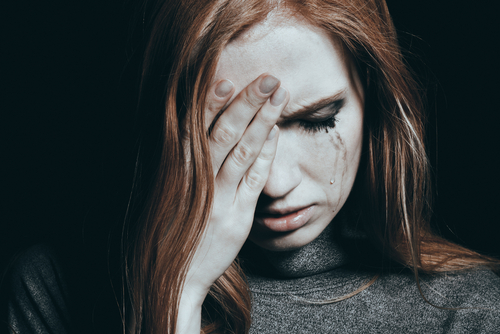 woman crying and holding forehead