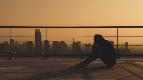 sad guy with head in hands in city