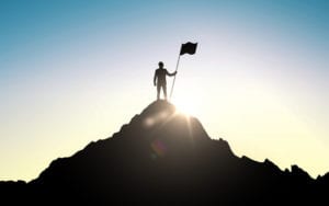 person with flag on top of mountain