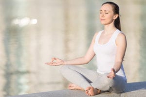 woman in white tank meditating