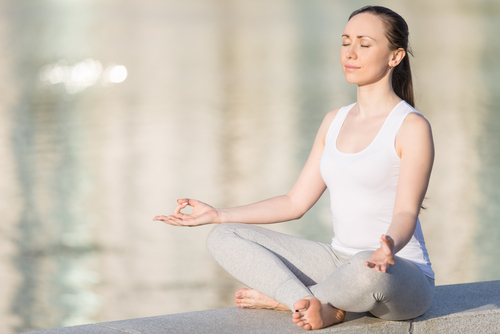 woman in white tank meditating