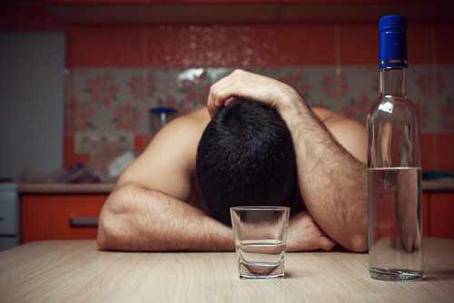 man with head down and bottle of alcohol