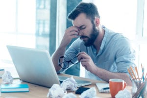 man pinching nose while at work