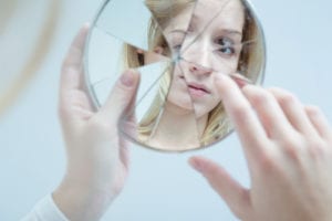 woman looking at cracked mirror