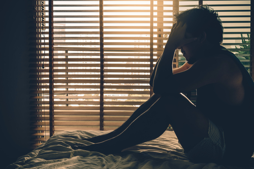 Man holding head in hands in bed