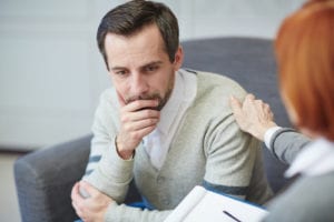 sad man comforted by counselor
