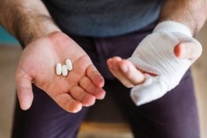 man with pain medicine and bandaged hand