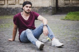 man-sitting-cobblestone-road