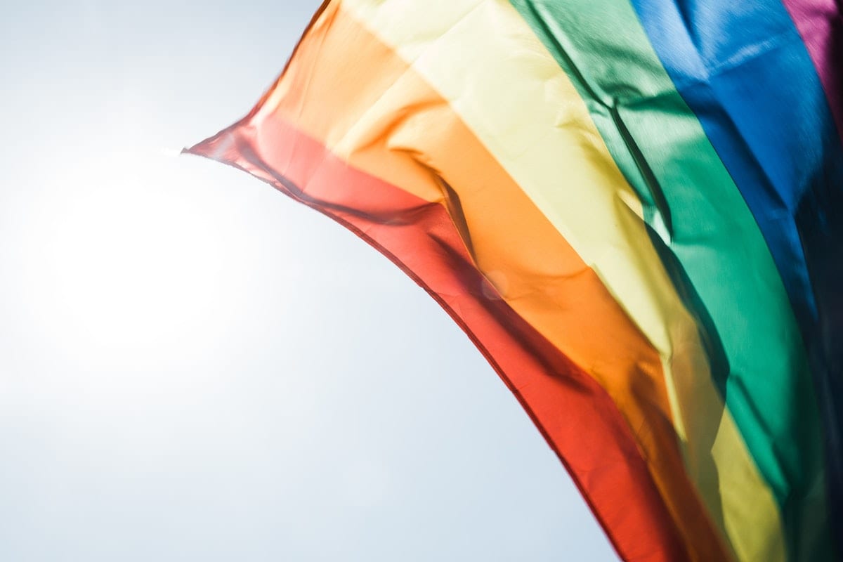 Rainbow pride flag flying in the daytime breeze.