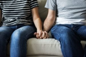 couple on couch holding hands