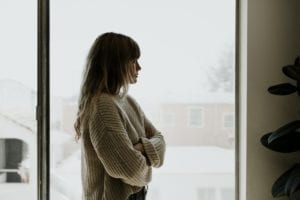 Sad woman staring out the window during a lockdown