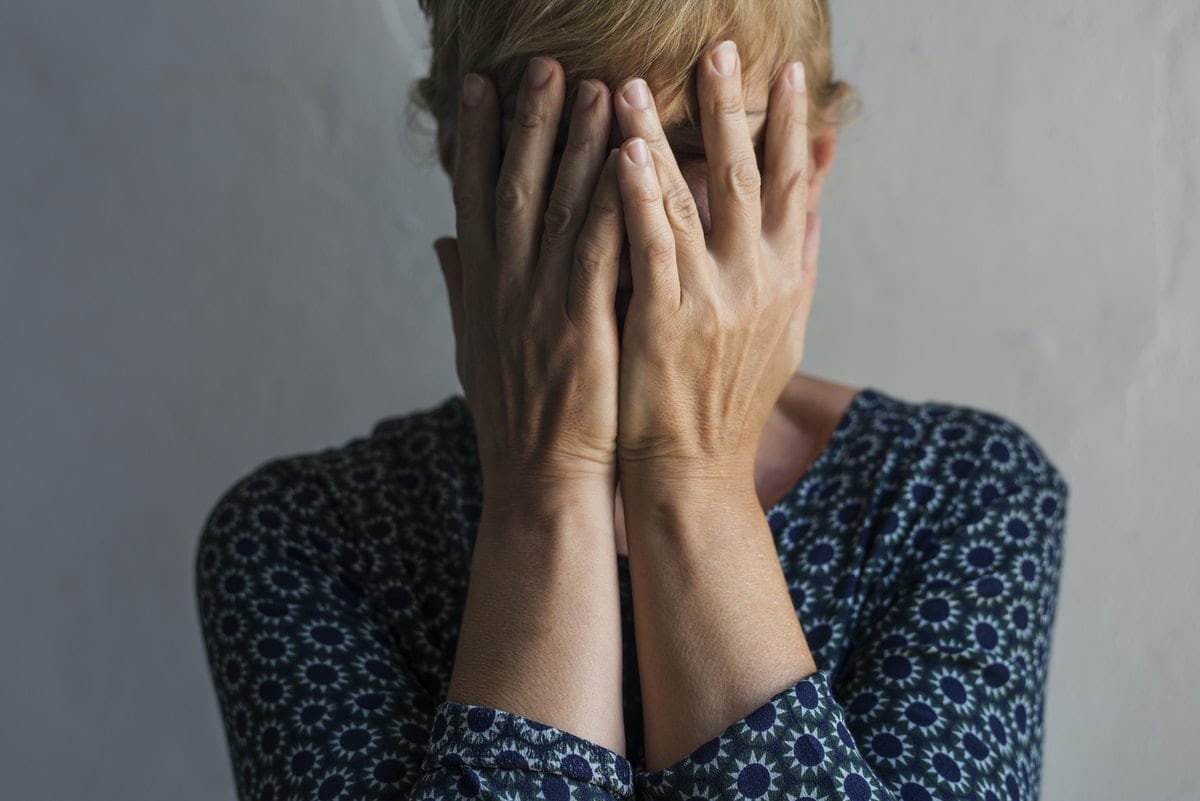 Elderly caucasian woman covering her face