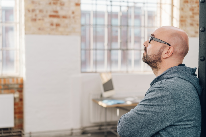 Bald man with glasses looking at the window