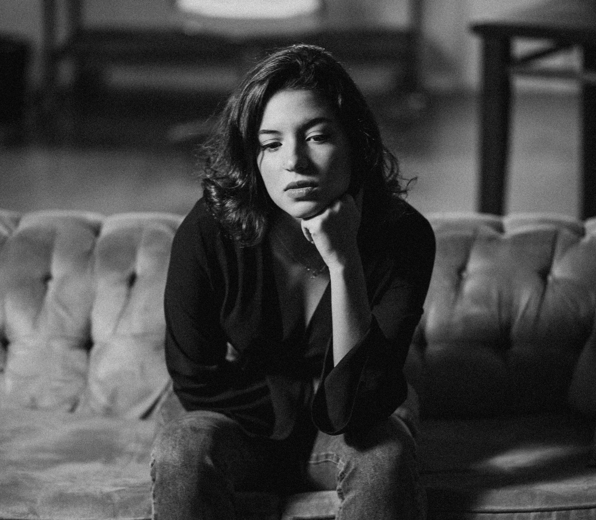 monochrome photo of thoughtful woman sitting on sofa