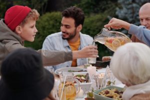 person pouring lemonade to boy during family dinner outdoors